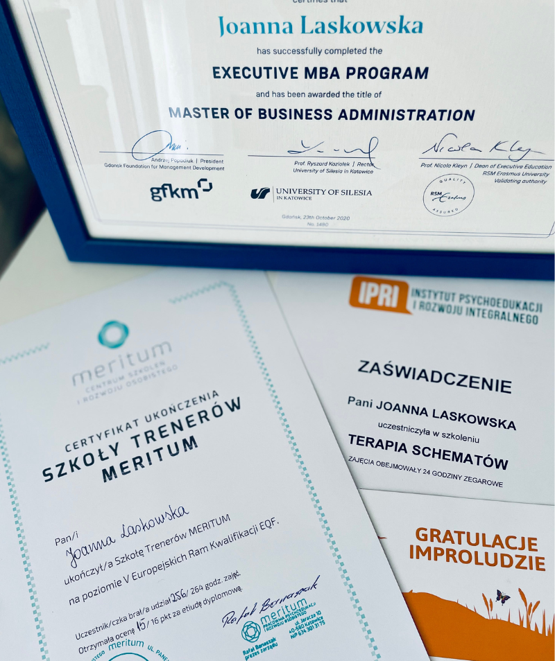 Zdjęcie dyplomów Joanny Laskowskiej. Widać między innymi napisy: Master of Business Administration, Szkoła Trenerów Meritum, Zaświadczenie - Terapia Schematów, Gratulacje Improludzie